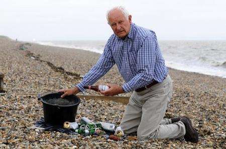 Ken West with the bucket of glass, cans and broken bottles he collected from the beach at The Leas, Minster