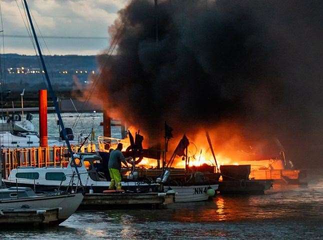 Fast action: Rob Willmott can be seen desperately trying to move a fishing boat away from the blazing vessel at Queenborough harbour. Picture: Henry Slack