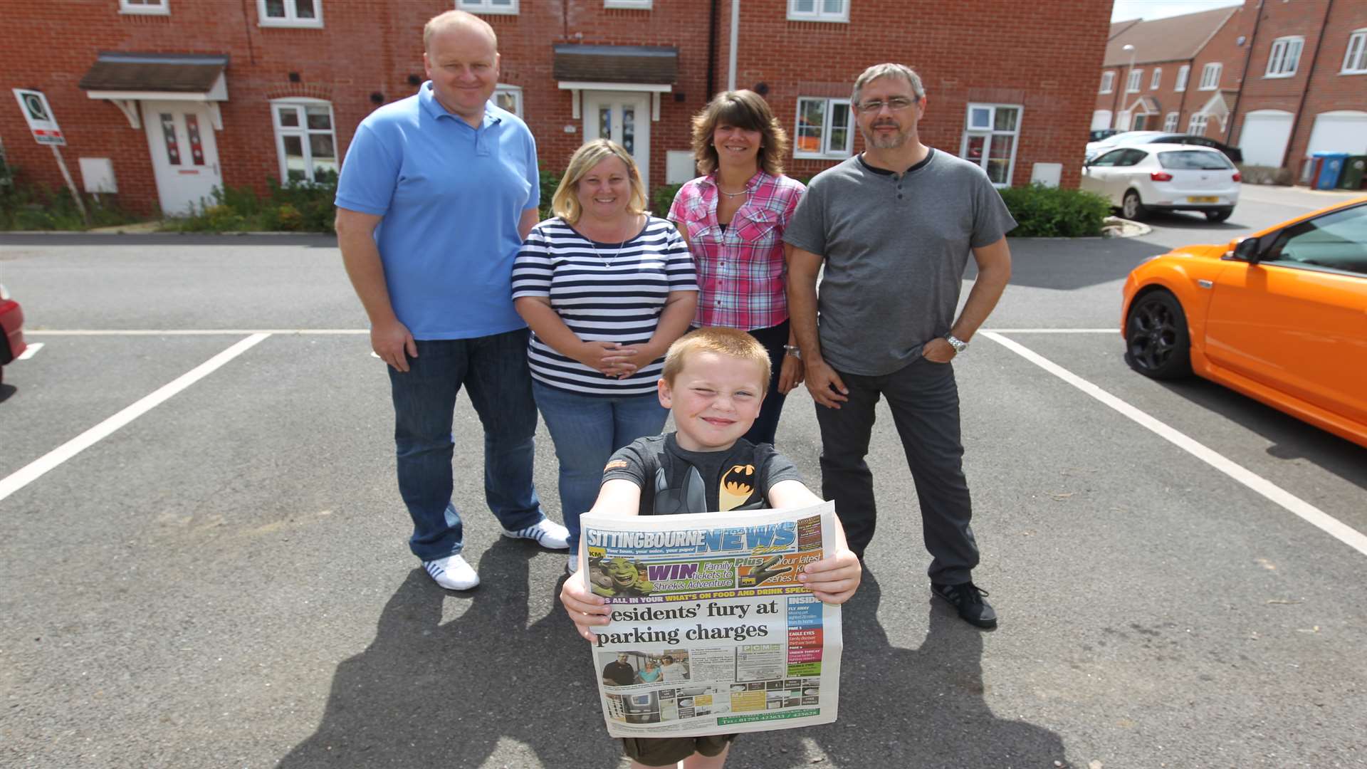 Oscar Stevens, six holds up a copy of the paper showing the battle his parents, from left, Gary Stevens and partner, Tina Deleslie, had with friends, Cheryl and Andy McGowan over parking spaces on the estate