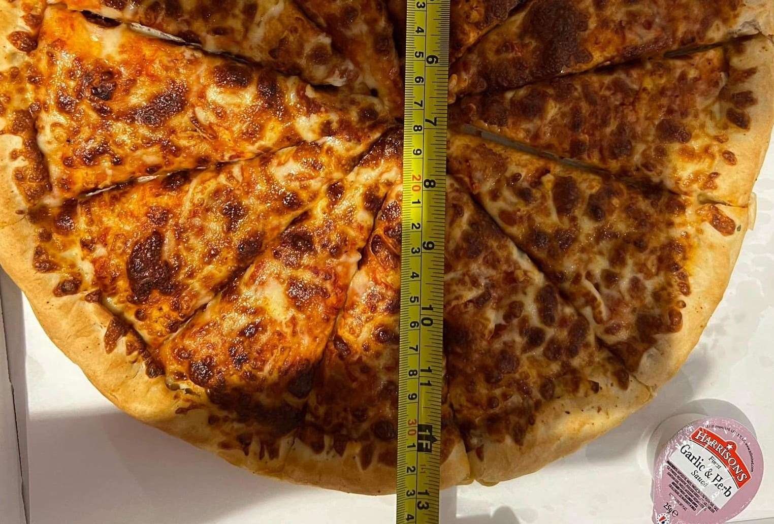 The customer used a tape measure to check the pizza's true size...and it was two inches short of advertised