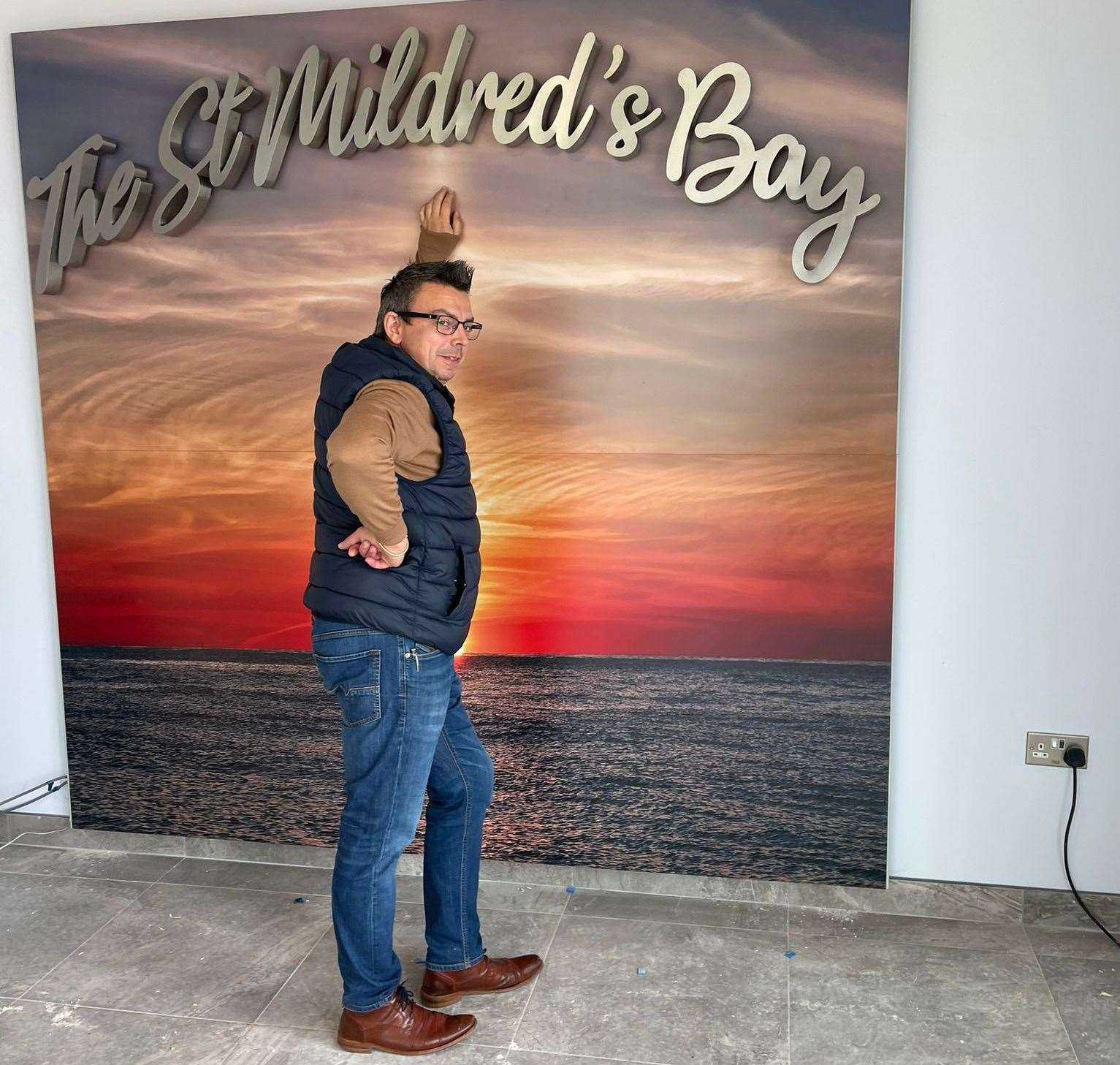 General manager Ben Garratt poses up in front of the feature wall