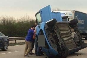 Witnesses help upright the car following a serious accident on the M20