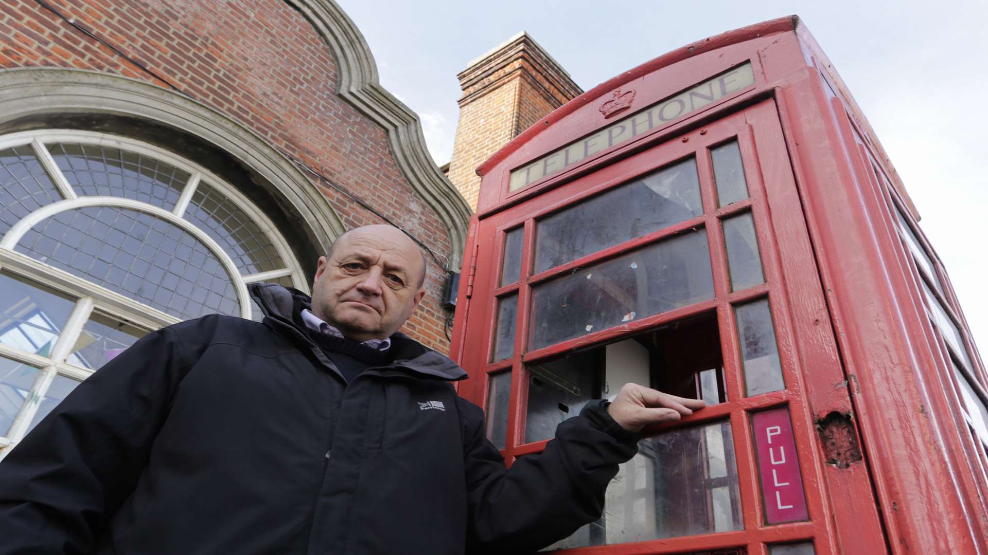 Former councillor Vince McMahan with the vandalised telephone box