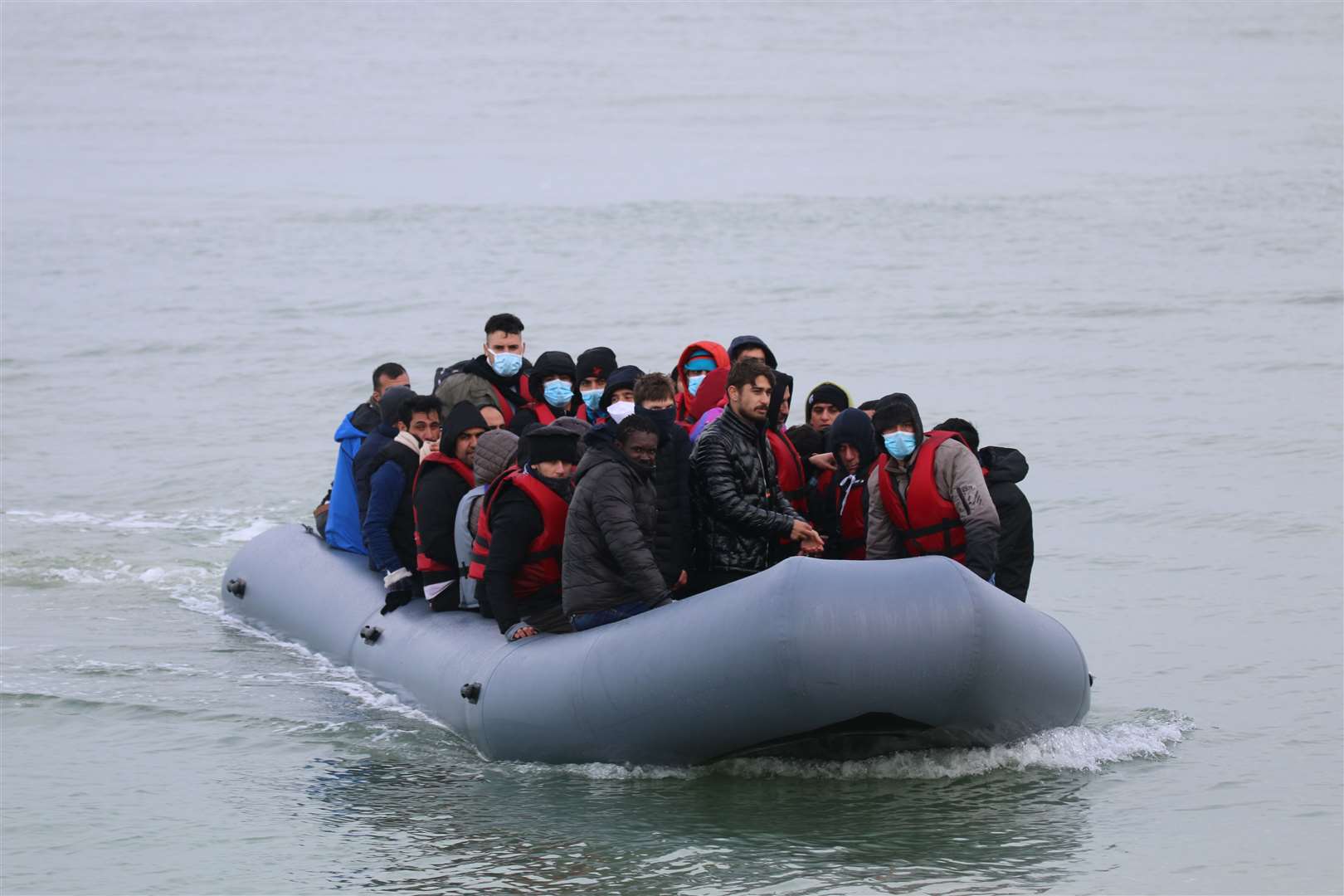 Asylum seekers on a small boat landing on a Kent beach