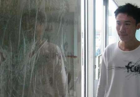 Jack Cheung beside a window damaged in the incident. Picture: GRAHAM RUSSEL
