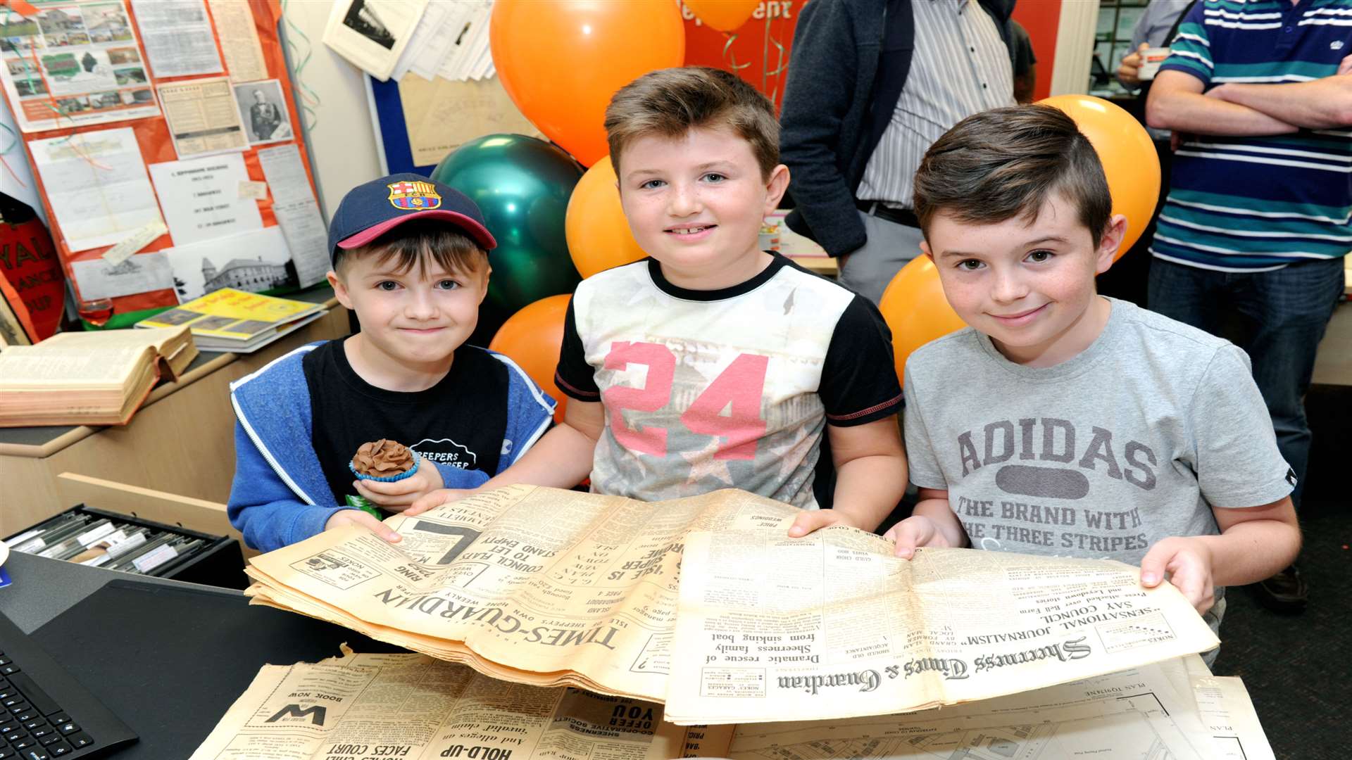 Max Cross, eight, Charlie Cross, nine, Max Broster, 10, with old copies of the Times Guardian.