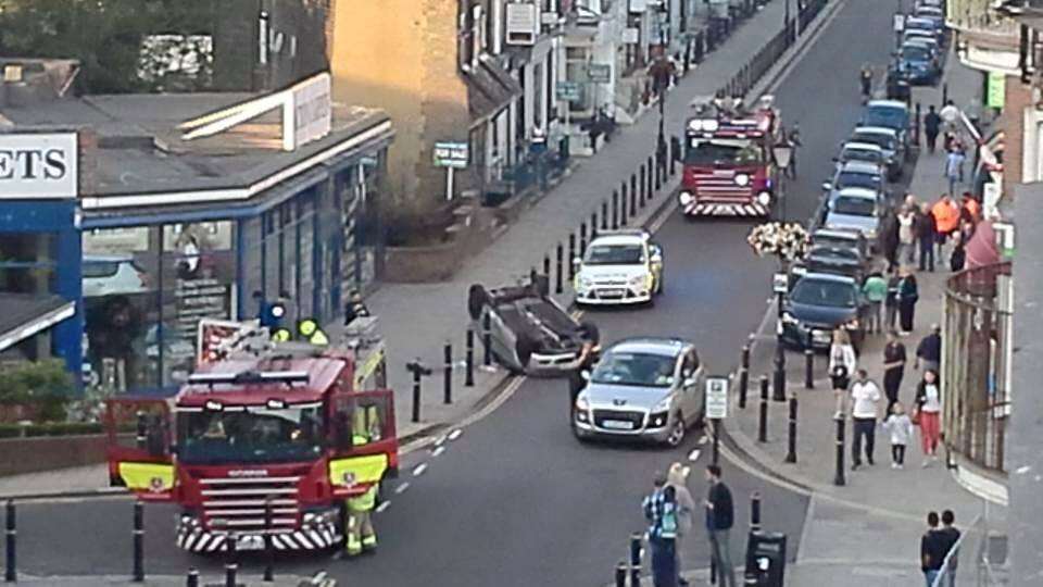 Car flips on to roof in busy town centre