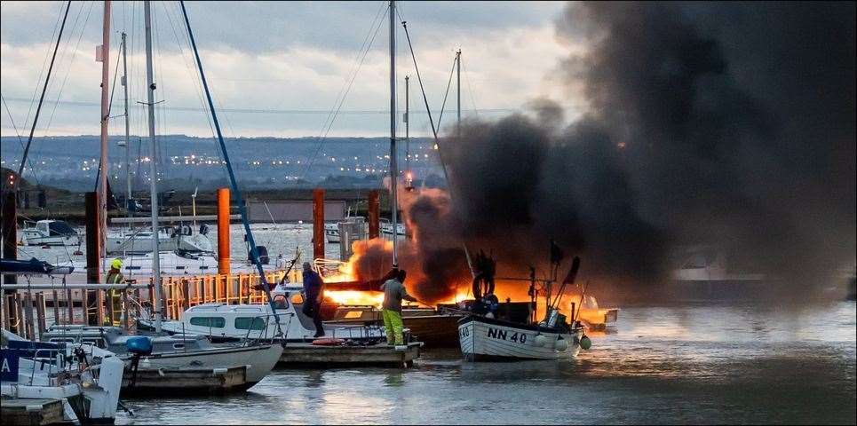 Firefighters and boat owners desperately try to put the flames out of a vessel which exploded at Queenborough marina. Picture: Henry Slack
