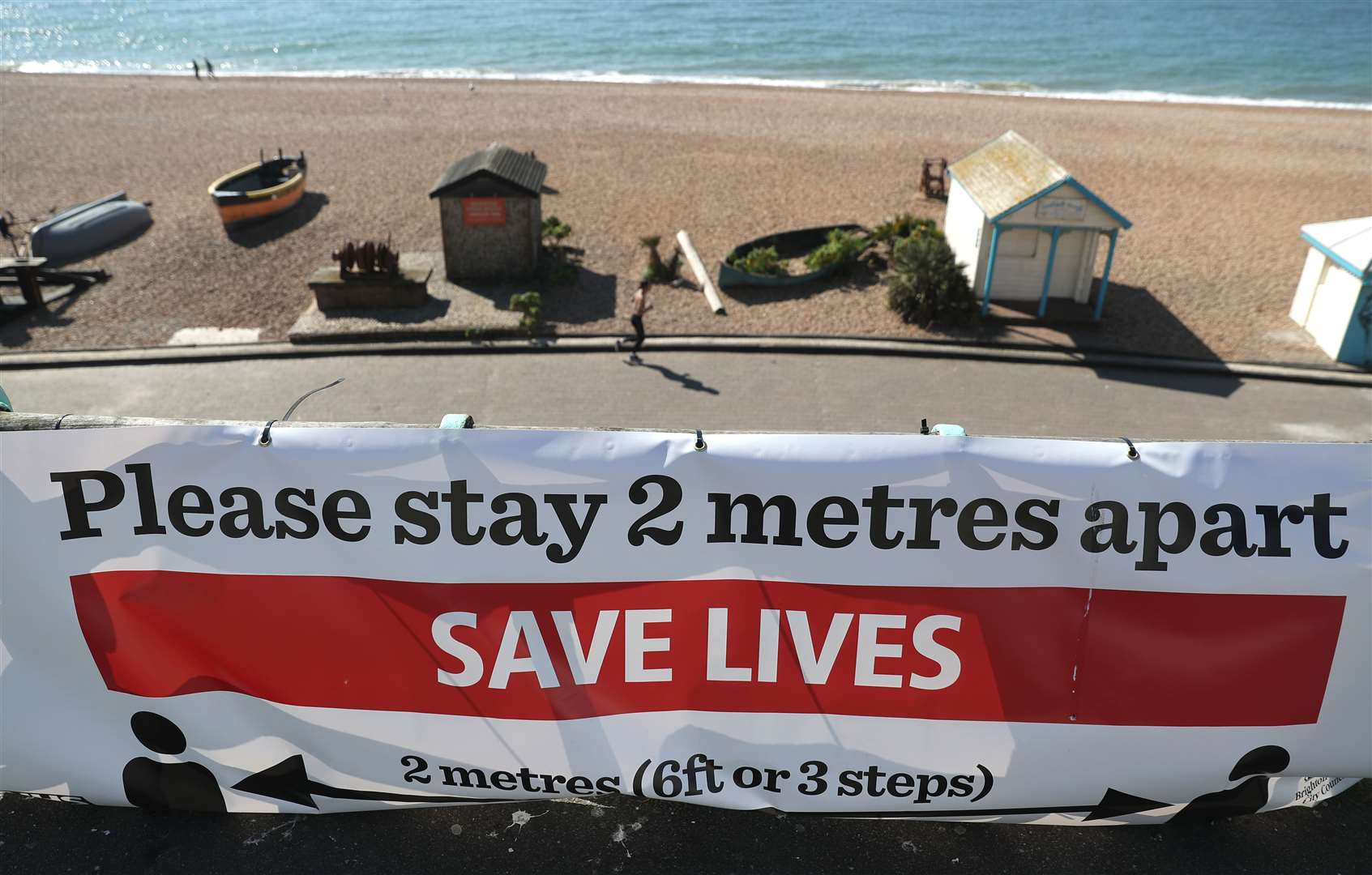 A ‘Please stay 2 metres apart’ sign on Brighton beach – the Government has reduced the restriction to ‘one metre-plus’ (Andrew Matthews/PA)