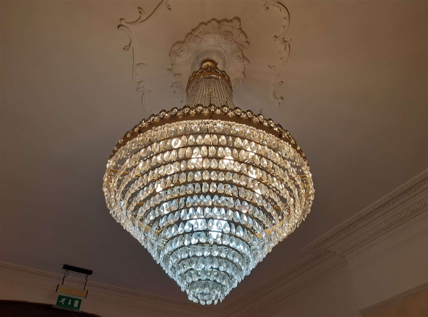 A beautiful chandelier, complete with an intricately carved ceiling, hangs in the kitchen