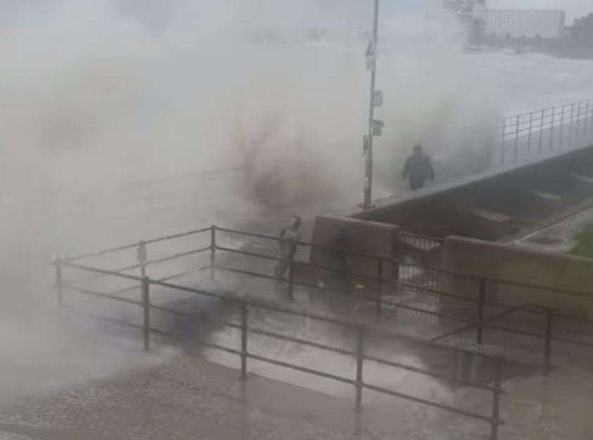 The man and the boys jog along the promenade in Folkestone as waves crash around them during Storm Ciaran