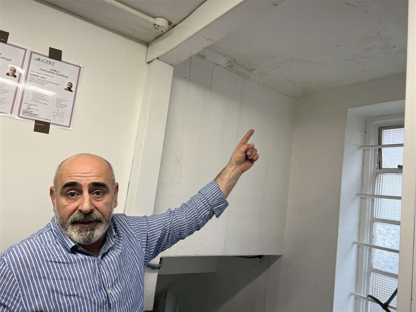 Baba Coban pointing at the water damage in the kitchen at the Cinar Kitchen in Sittingbourne. Picture: Megan Carr
