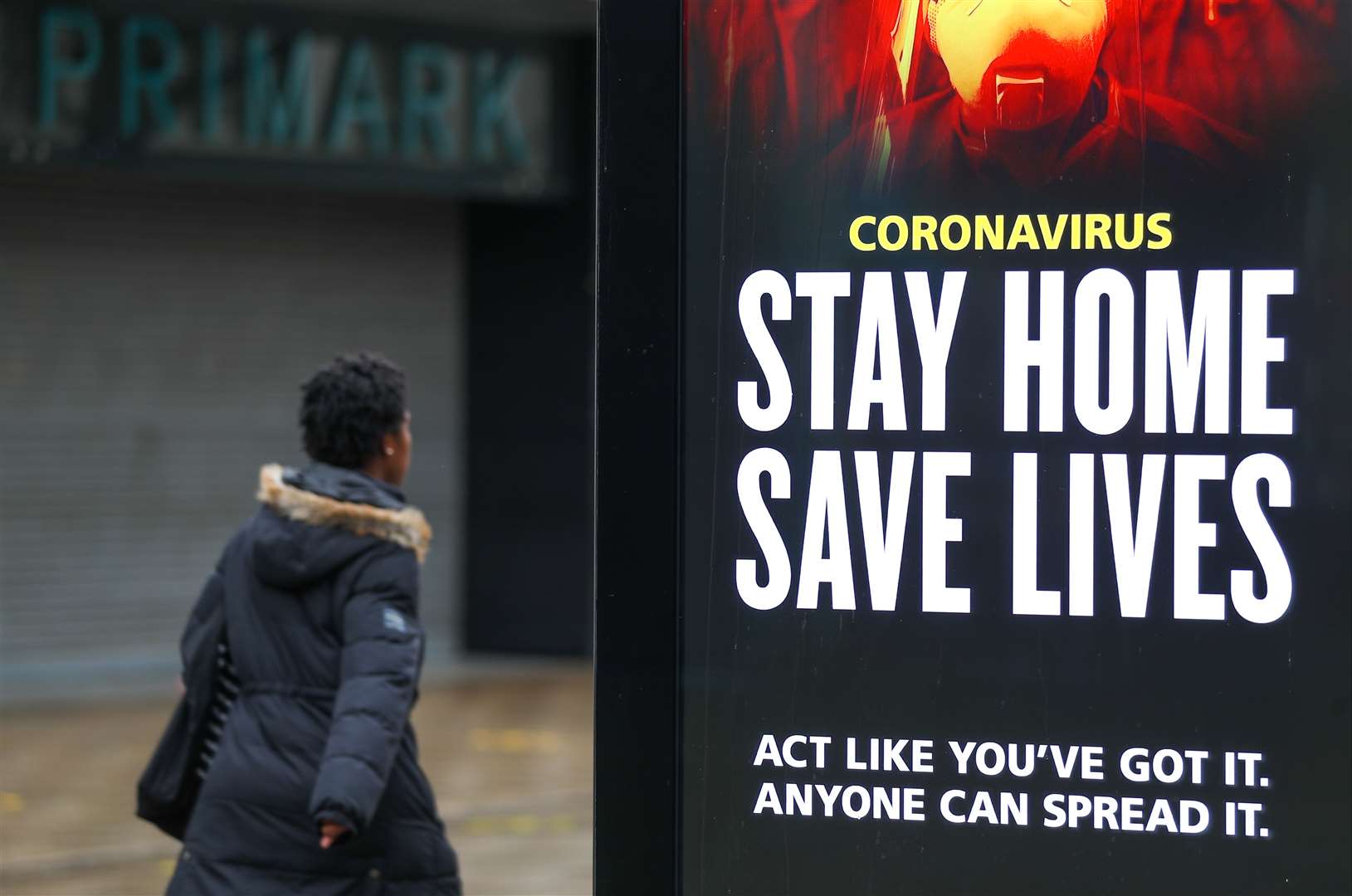 A person walks past a Stay Home Save Lives sign on Commercial Road in Portsmouth (Andrew Matthews/PA)