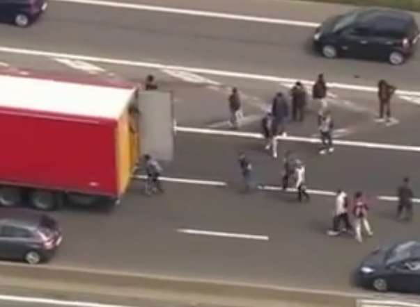 Migrants try to board a lorry outside Calais. Picture: Still taken from BBC video