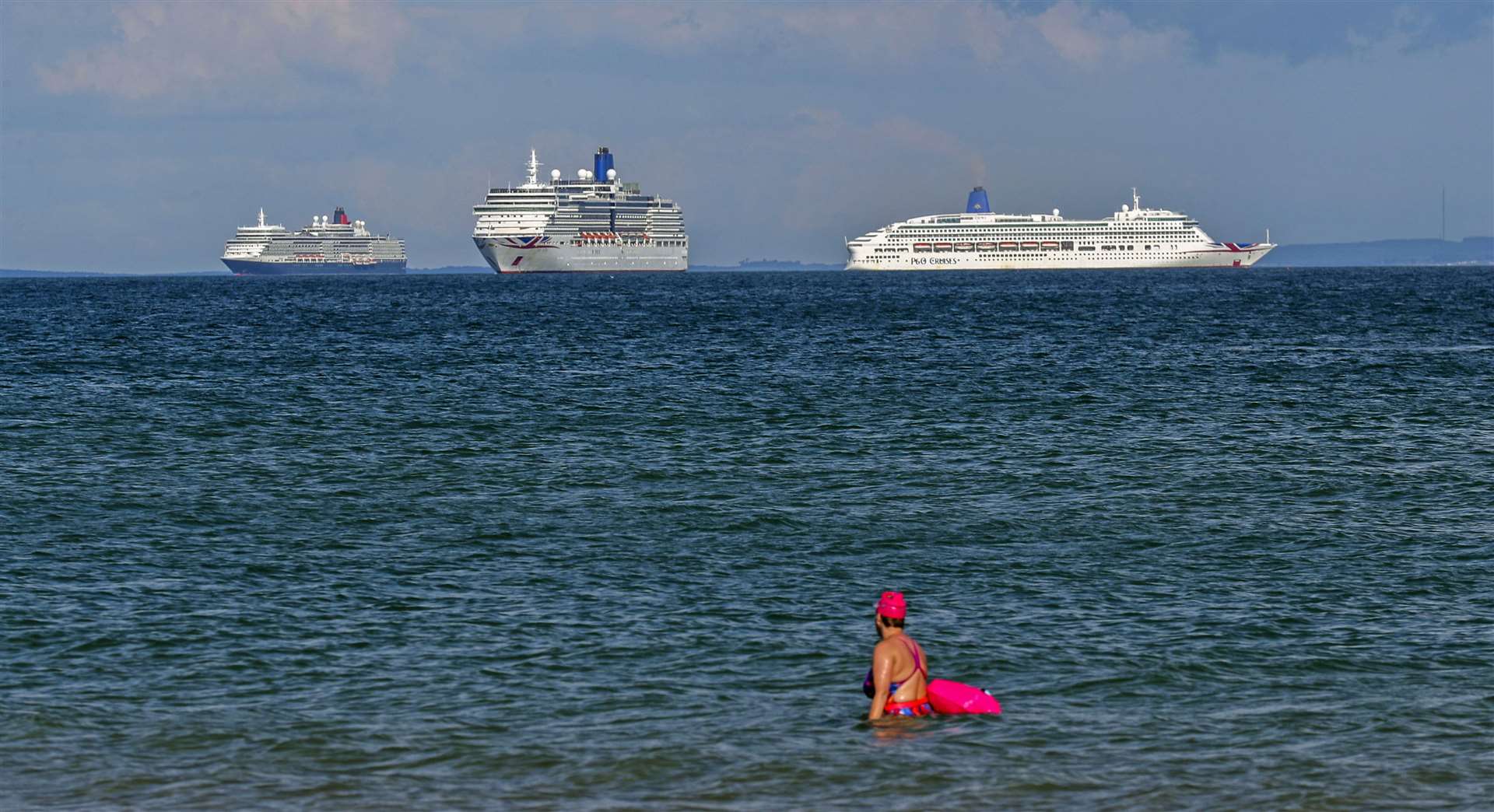A swimmer in the water at Sandbanks looks out at the cruise ships Queen Elizabeth (left), Arcadia and Aurora (Steve Parsons/PA)