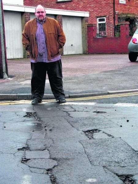 Cllr Alex Perkins by potholes in Canterbury