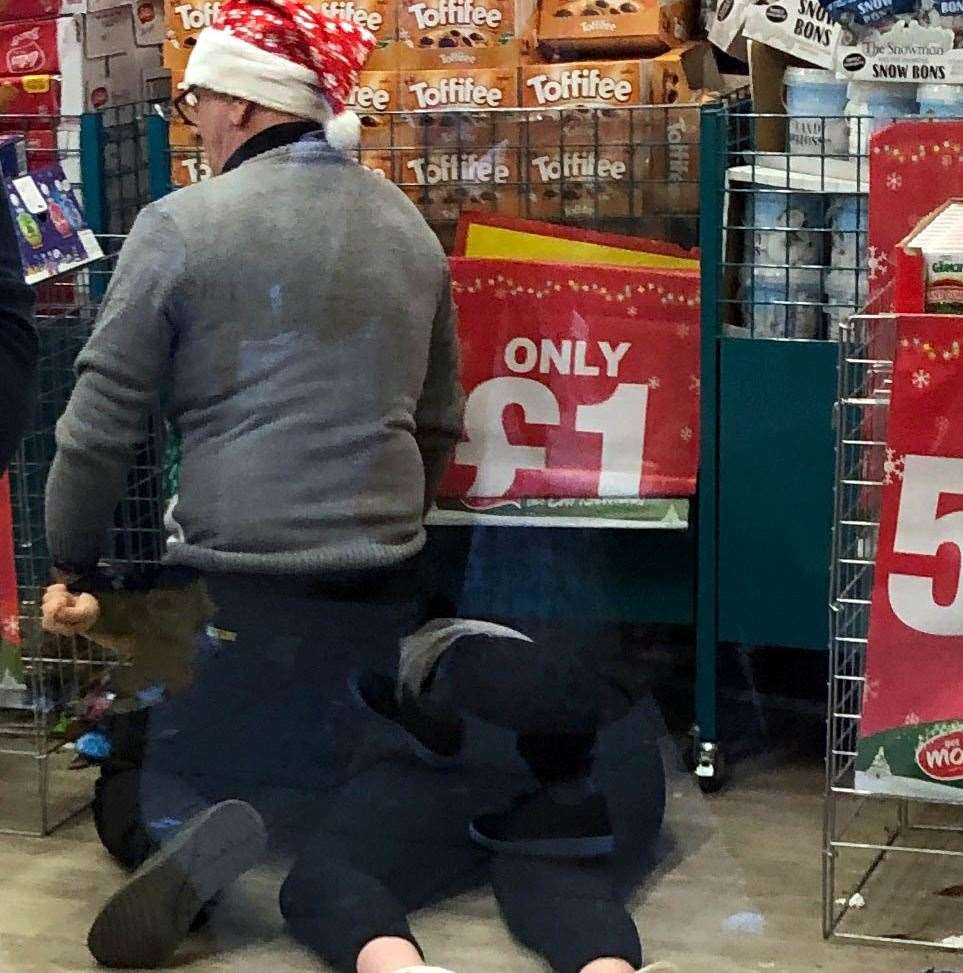 A shop worker wearing a festive hat was photographed pinning a person to the floor inside the shop. Picture: Uknip