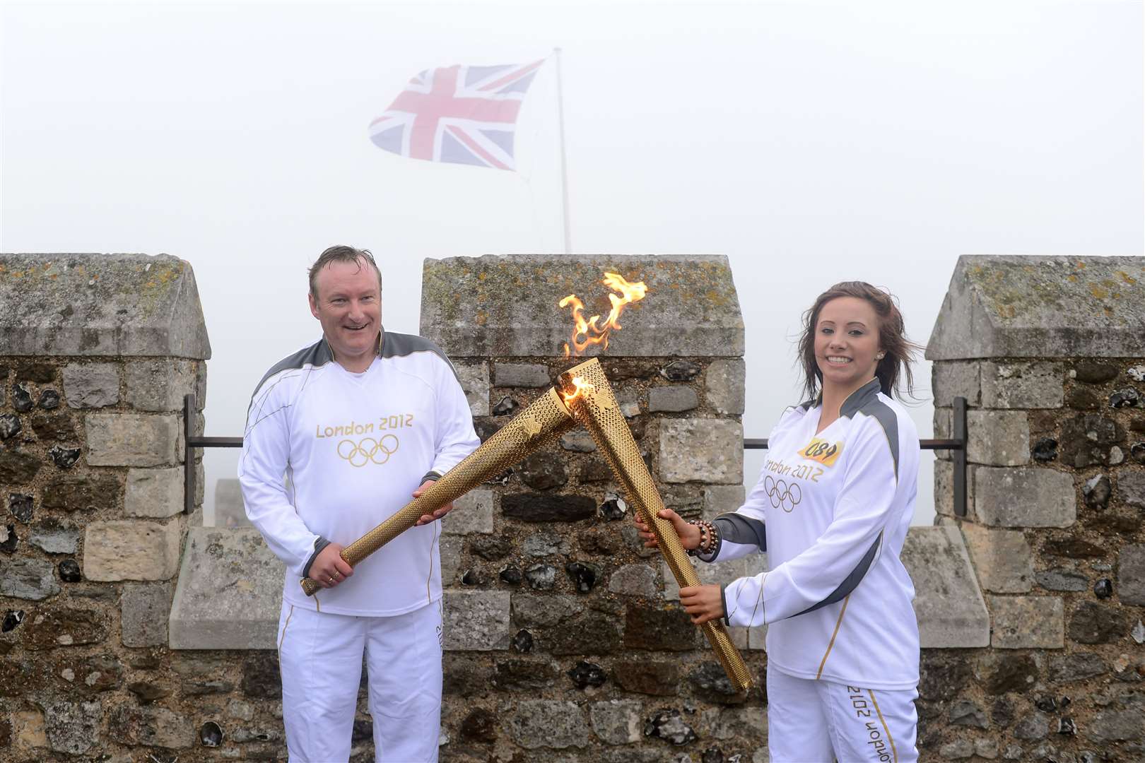 Graham Hutchison passes the flame to Sophie Waller at the top of Dover Castle during day 61 of the relay