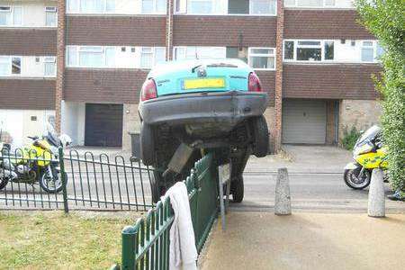 Residents looked on after the car mounted the railings in reverse