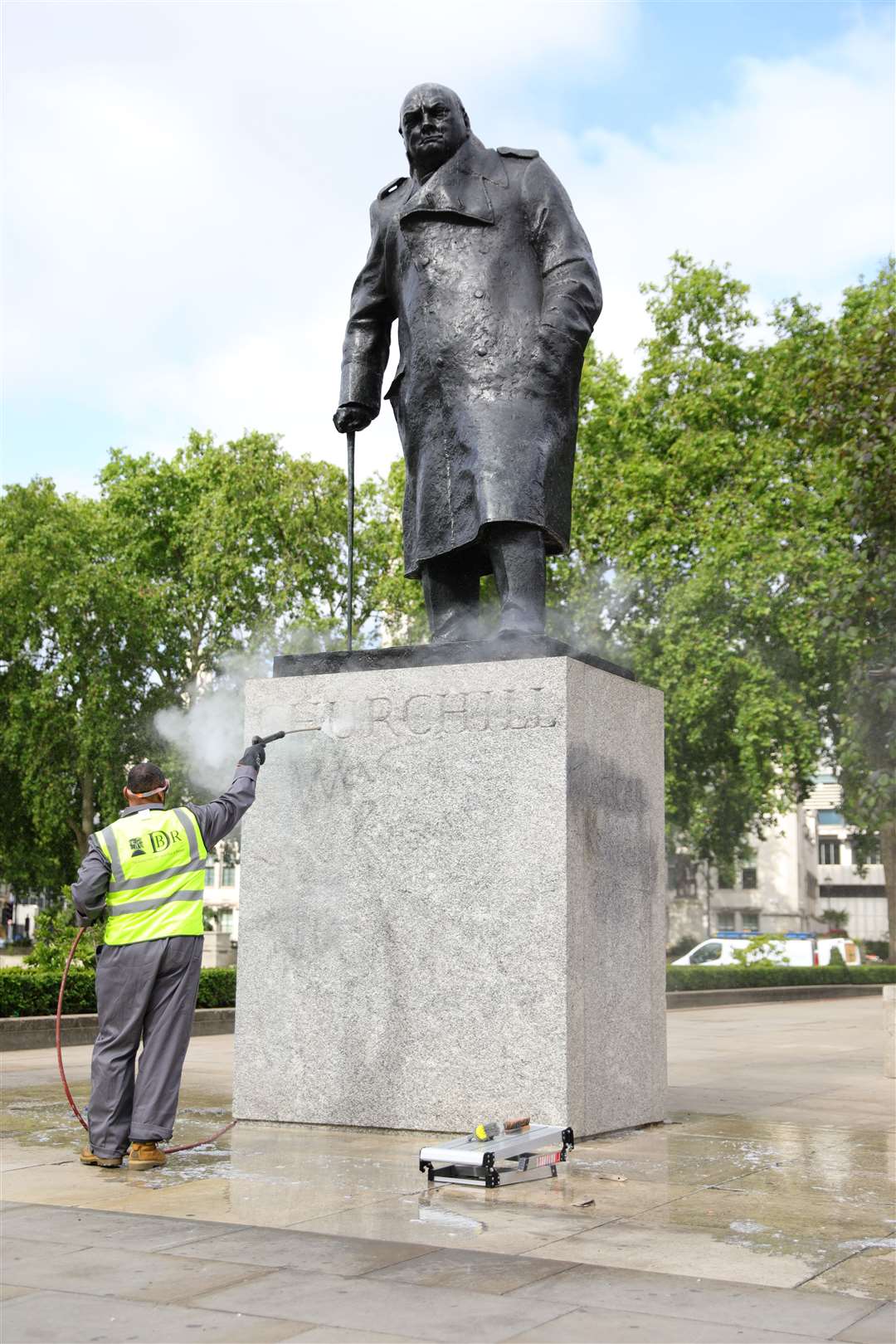 A worker cleans graffiti from the plinth of the statue of Sir Winston Churchill at Parliament Square (PA)