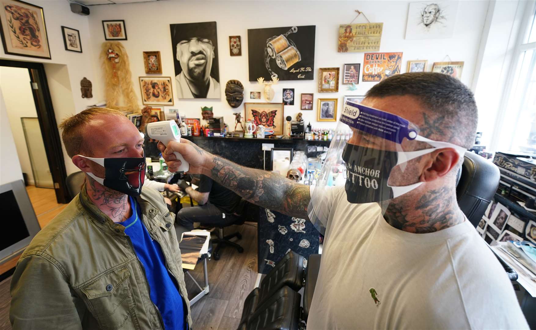 Tattoo artist Dan Ridgewell takes the temperature of a customer at the Axe & Anchor tattoo shop in North Shields, North Tyneside (Owen Humphreys/PA)