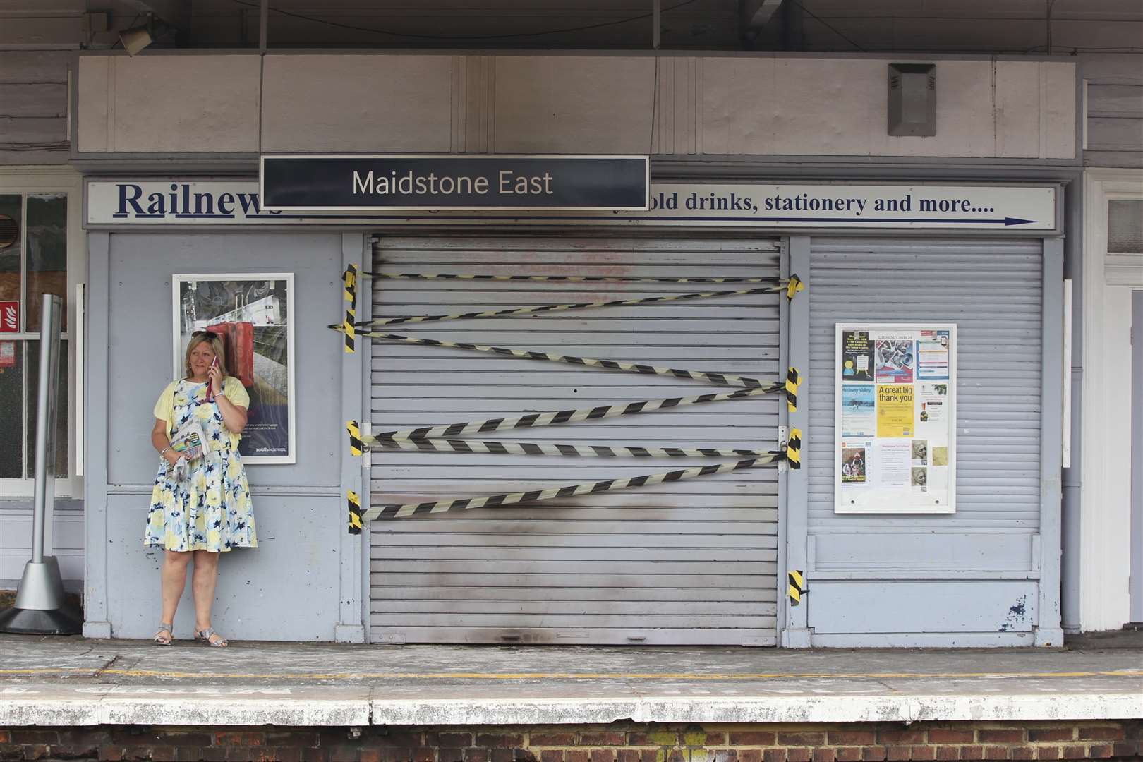 A woman stands next to the fire-damaged newsagents