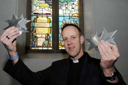 Dover St Mary's church,Rev David Ridley holds up Stars against the Herald Window.