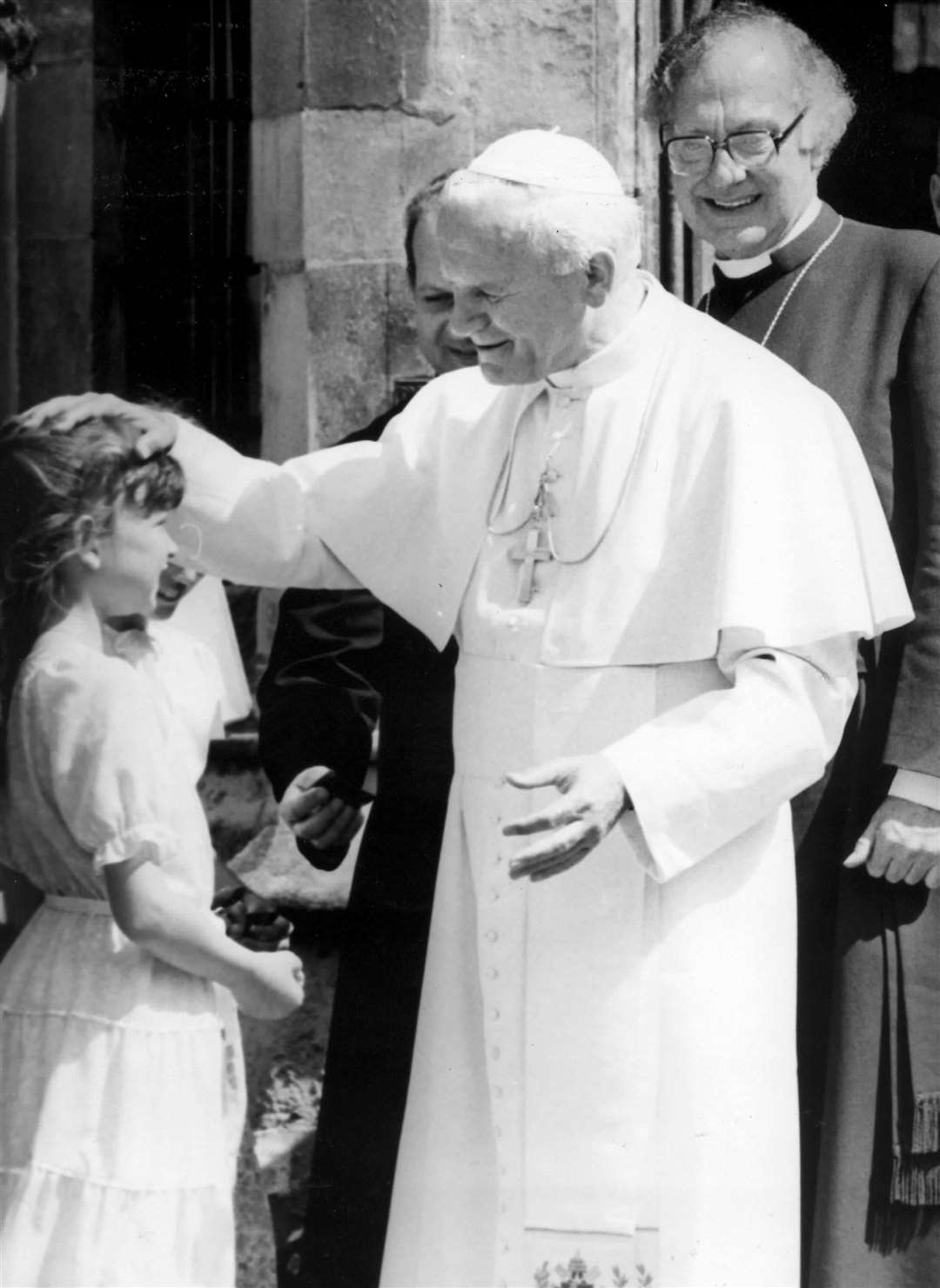 Pope John Paul II blesses a young girl outside the Cathedral as Archbishop of Canterbury Dr Robert Runcie watches on in June 1982