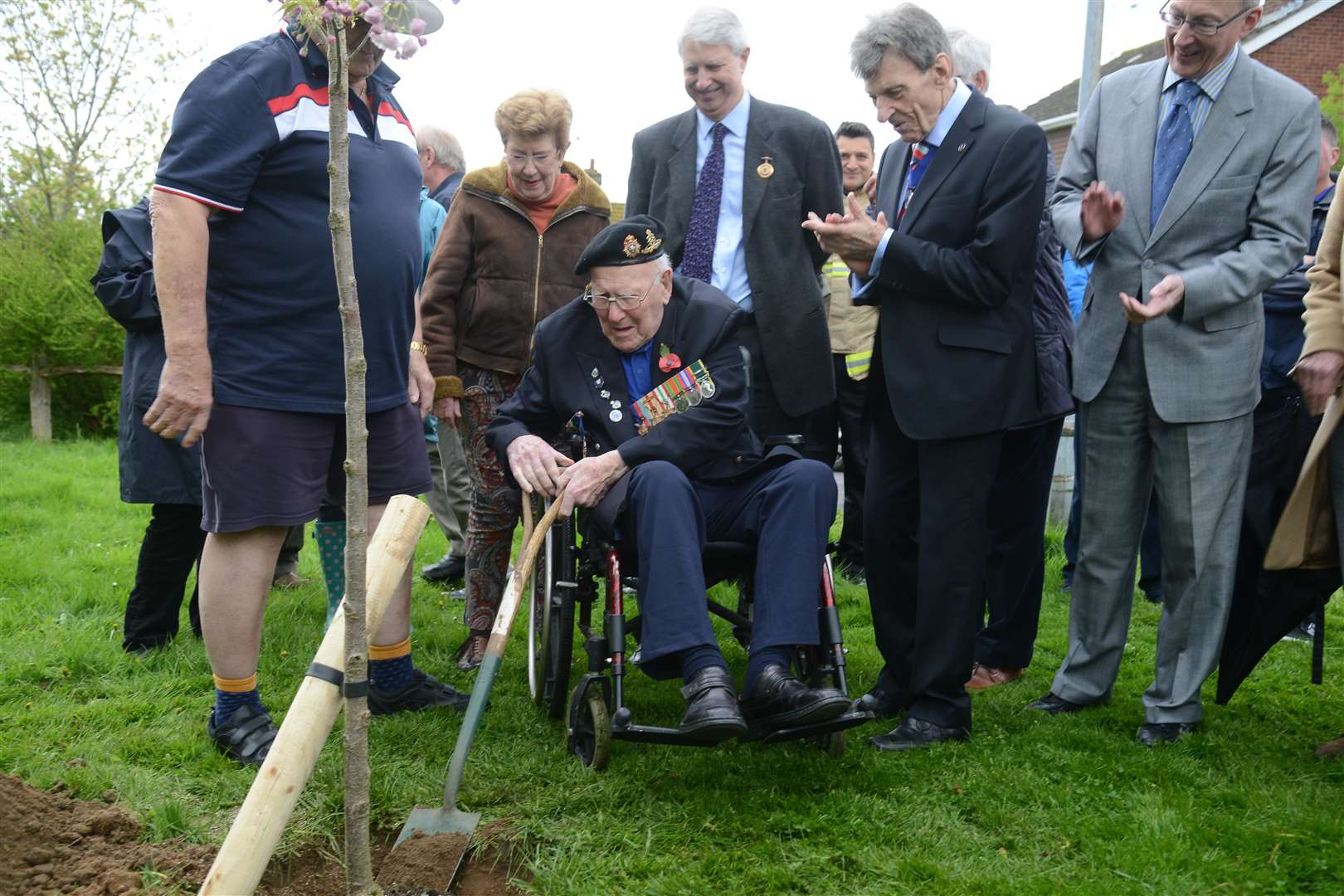 Cllr Richard Parry watches as Harry Garrett shovels earth at the base of his tree.