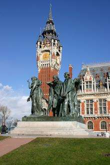 Calais Town Hall with the iconic clock tower and belfry. The statue in the foreground is of the potentially sacrificial burghers.