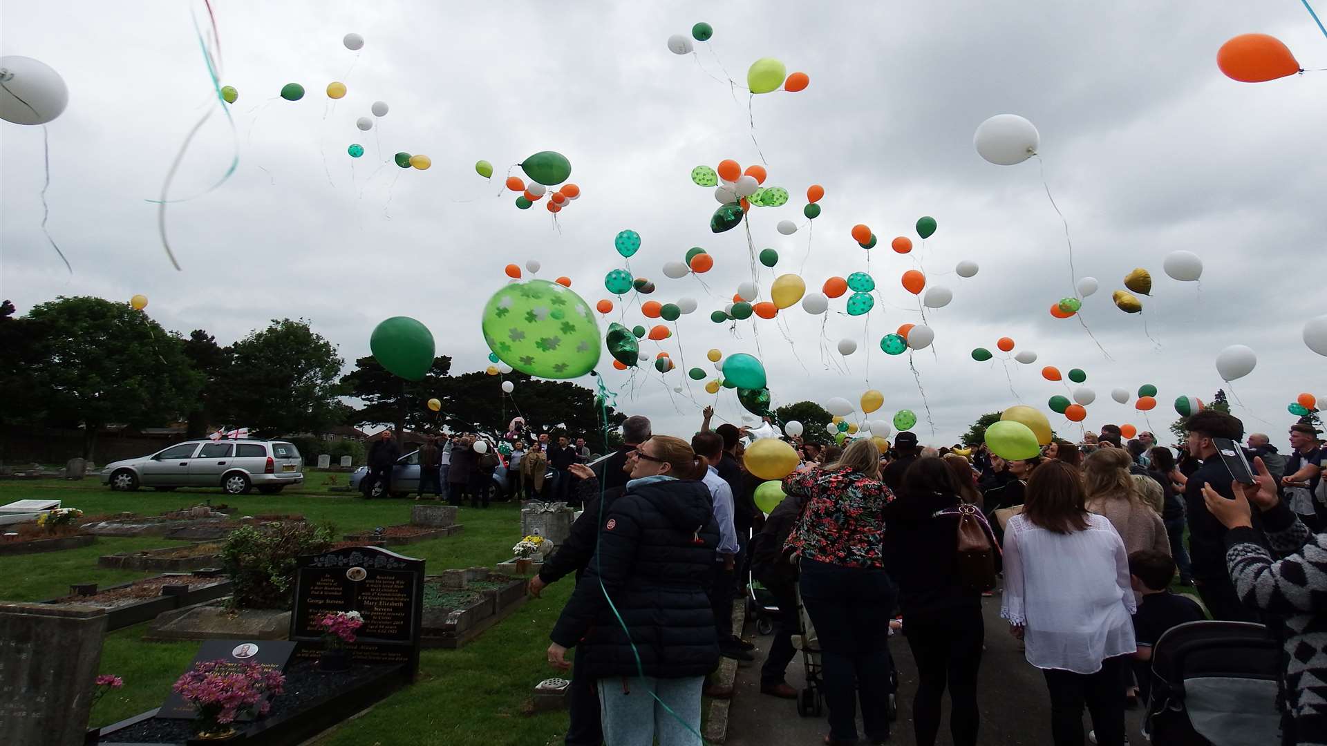 Hundreds of orange, white and green balloons were released