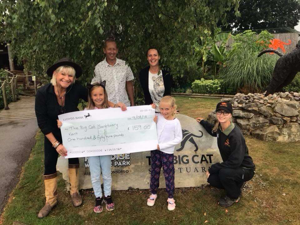 Isabella Miller, 7, handing over the money to Sanctuary staff with dad Matthew, mum Kate and younger sister Francesca.