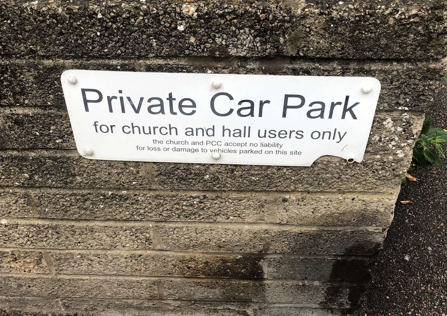 A sign stating it is a private car park on the wall outside