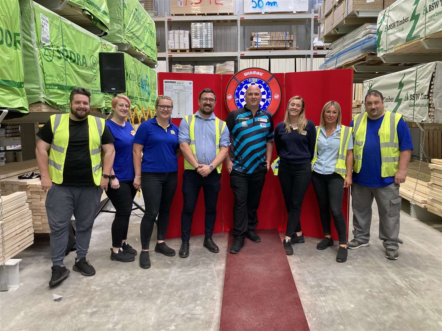 The team take a break at the Selco Builders Warehouse for a picture with champion darts player Rob Cross
