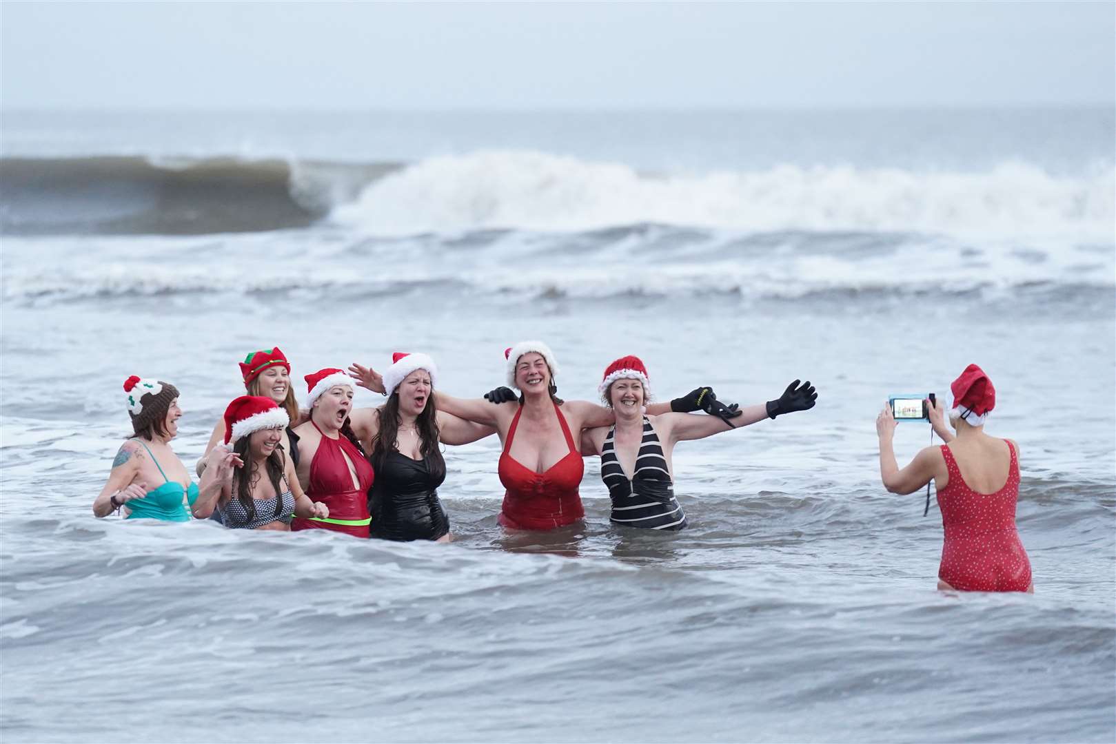 Swimmers pose for a photo as they take part in the Christmas Day swim at Tynemouth, North Tyneside (Owen Humphreys/PA)