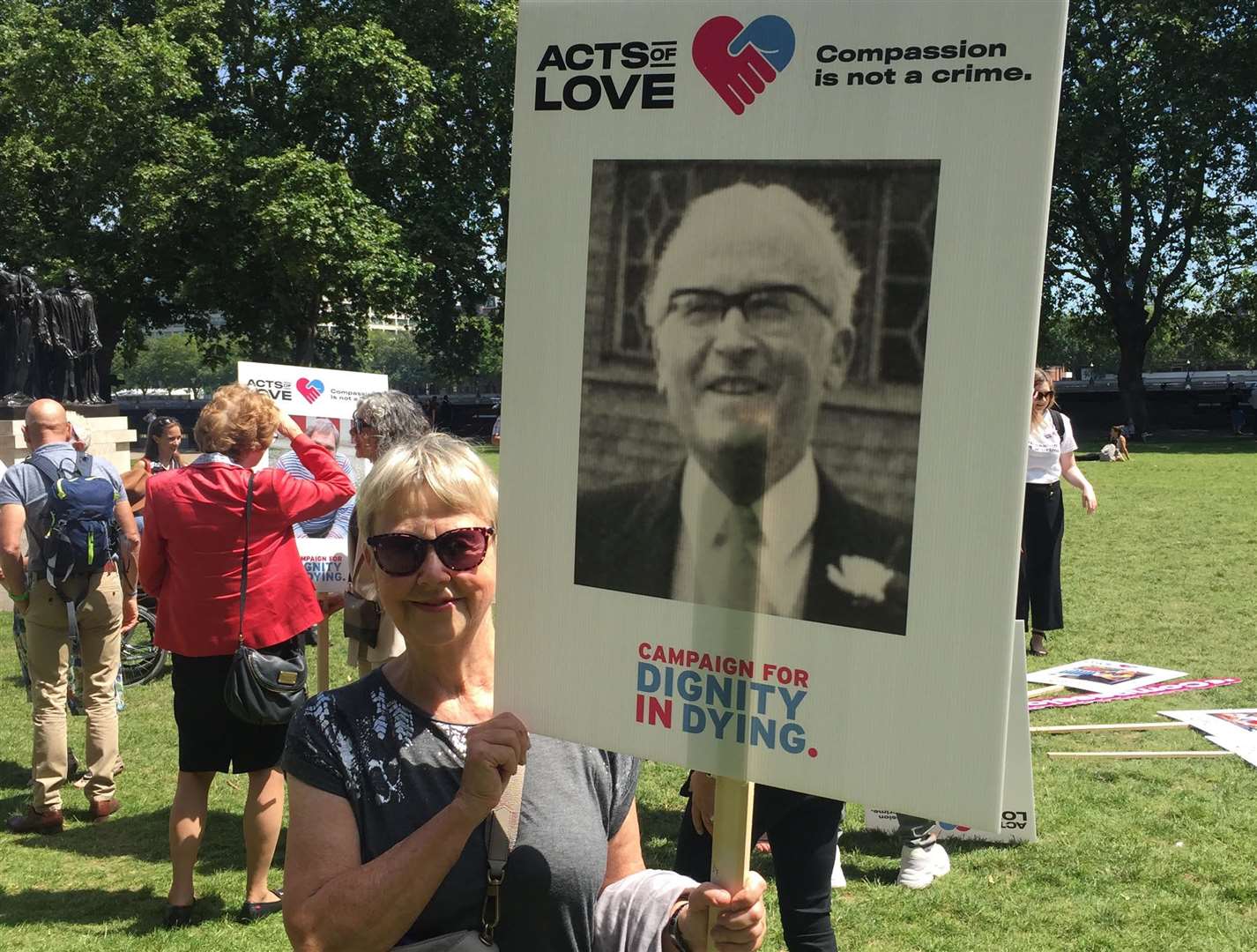 Suzanne Jee at a rally outside Parliament in 2019, with a placard featuring a photo of her father