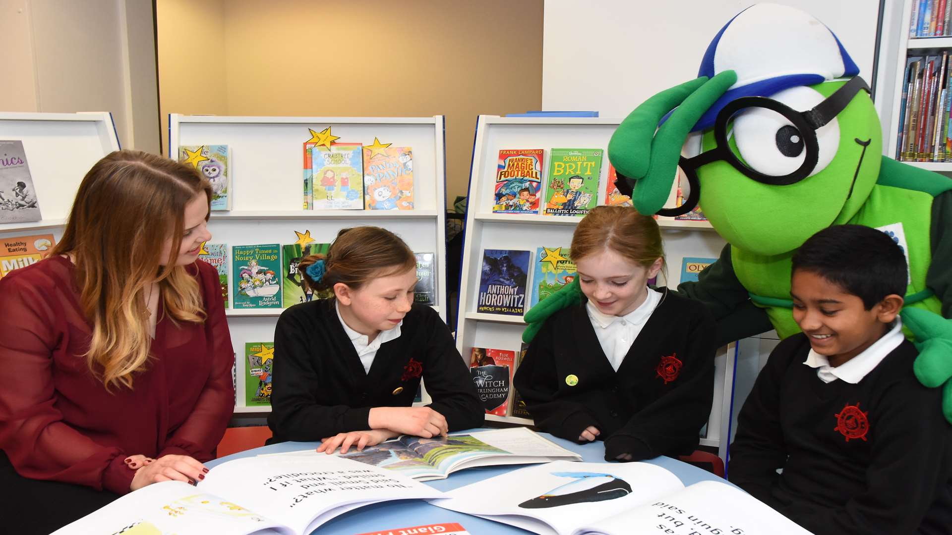 Amie Snowden of Kent Reliance enjoys storytelling with bookworms from Whitstable Junior School and KM Charity Team mascot Buster.