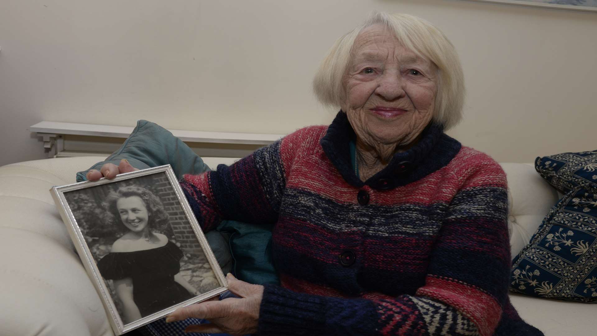 Clara now, aged 92, holding a picture of herself taken 70 years ago