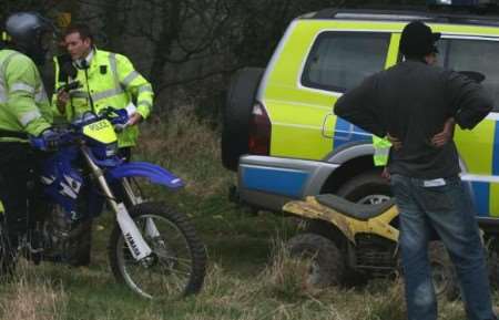 Police officers stop and seize a yellow quad bike