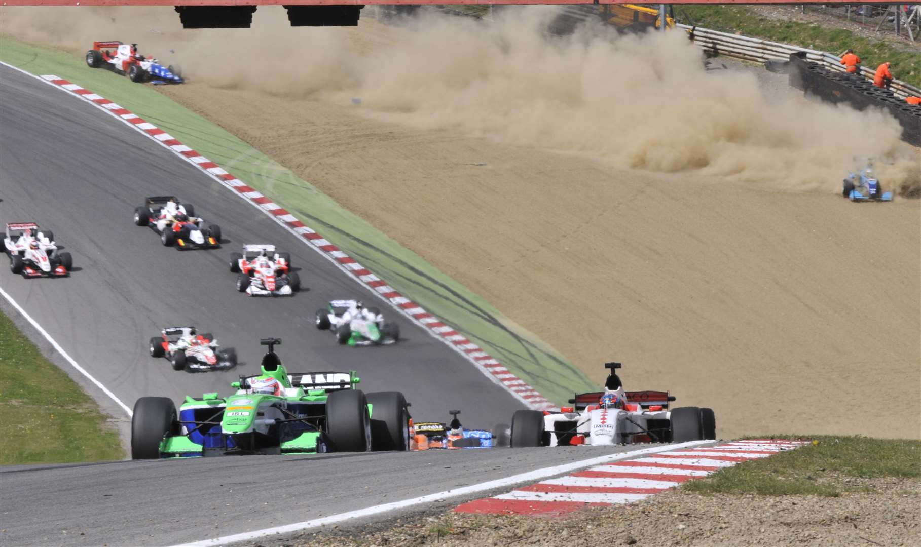 As Ireland's Adam Carroll leads the feature race, India's Narain Karthikeyan hits the gravel at Paddock Hill Bend in 2009. Picture: Andy Payton