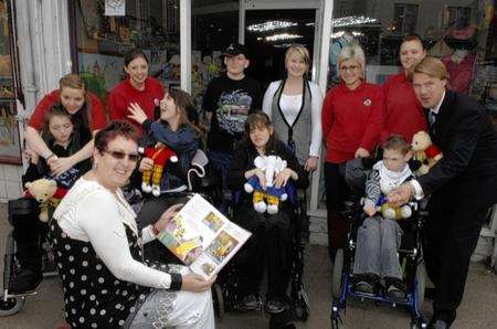 Shop manager Shirley Clarke with one of the Rupert books and children and staff from Kent Kids Miles of Smiles outside the Kent Kids Dreams charity shop in Oxford Street Whitstable which has recieved a massive donation of Rupert memorabilia.