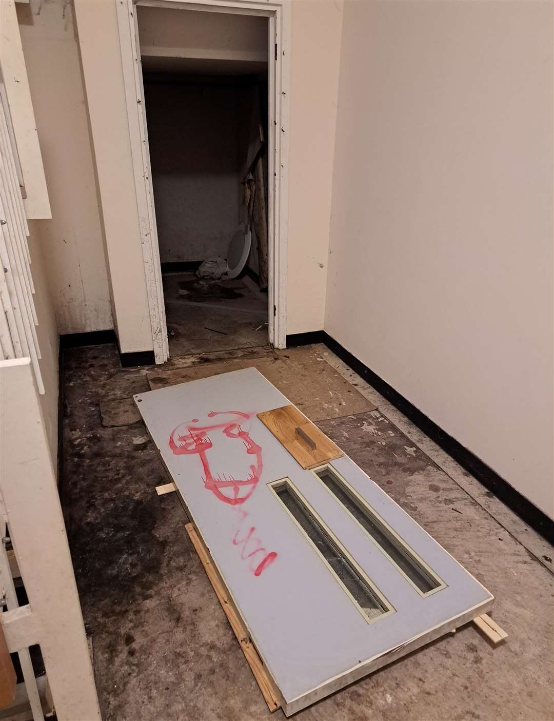 A knocked down door with an obscene drawing on it