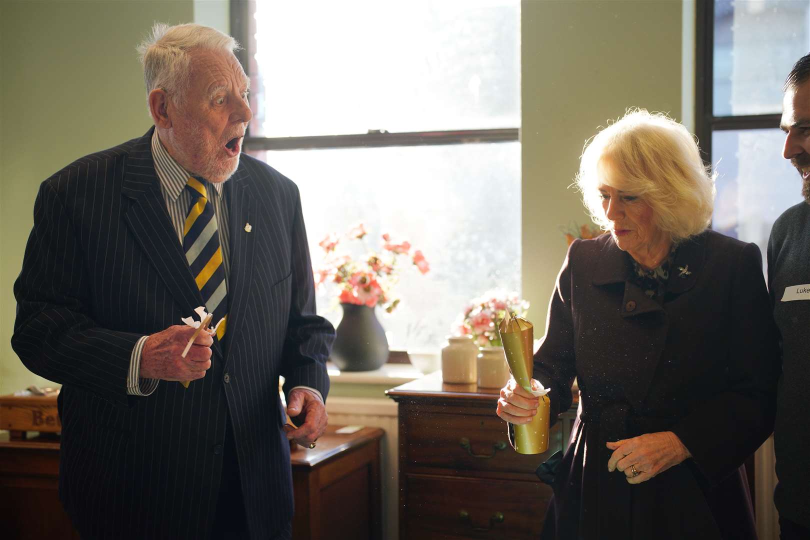 Camilla pulled a Christmas cracker with Emmaus UK patron Sir Terry Waite during her visit (Ben Birchall/PA)