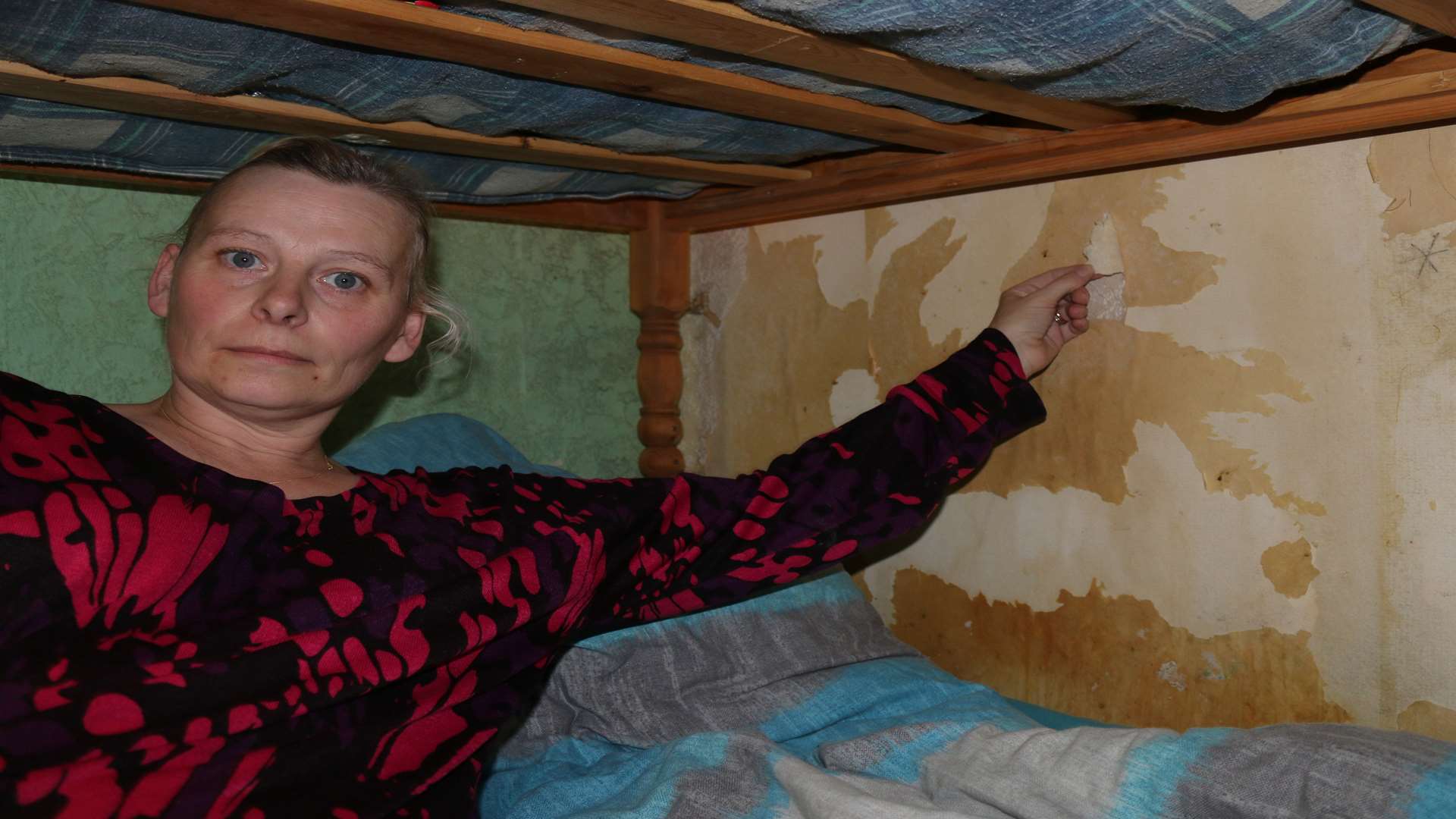Sinead De Lobel in her eldest son's bedroom with damp, peeling wallpaper and bare walls