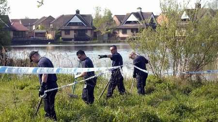 Police officers conducting a search for clues beside the lake. Picture: GARY BROWNE