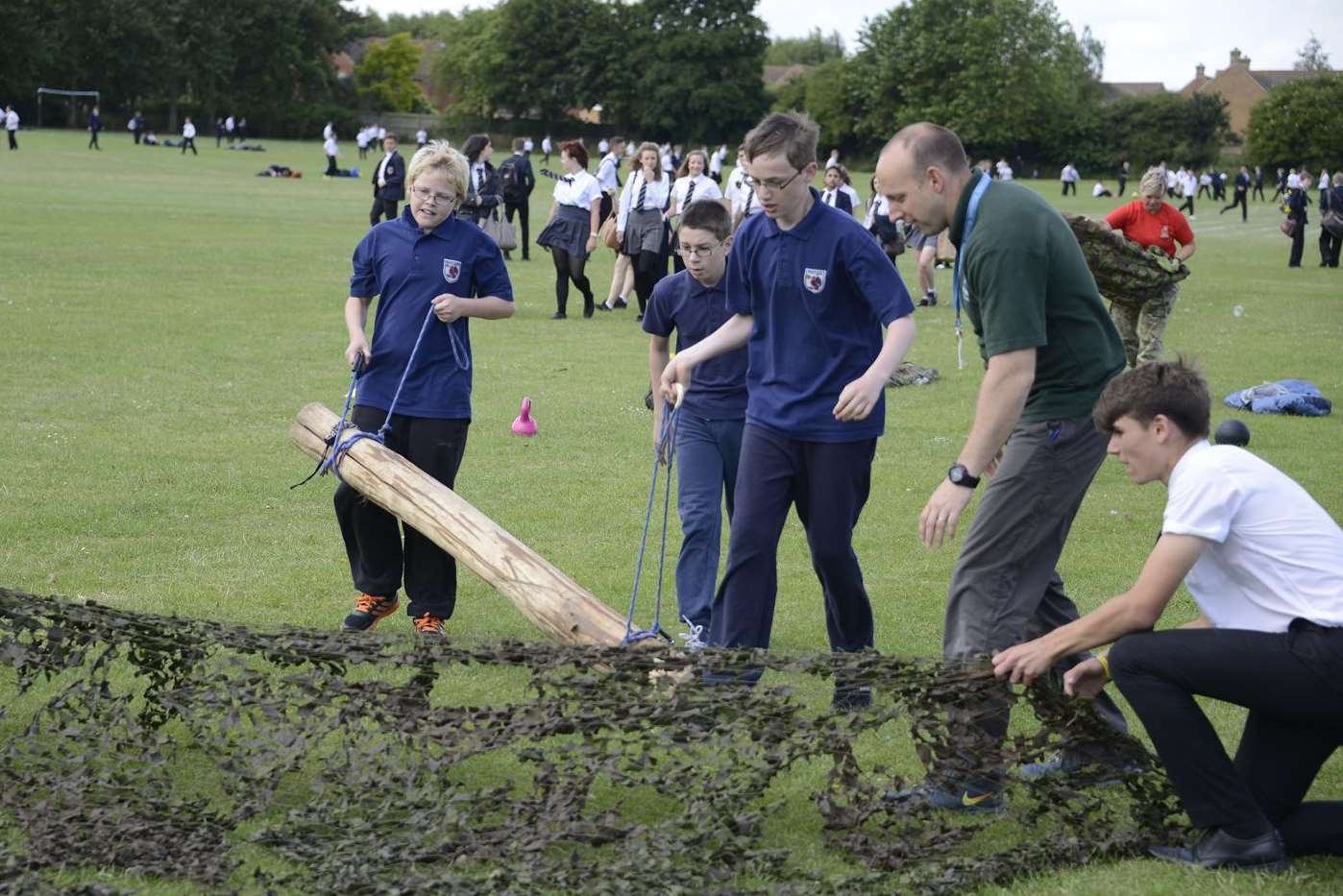Westlands School Iron Man challenge with Year 7 and 8 pupils grabbing a log and dragging it under three cargo nets