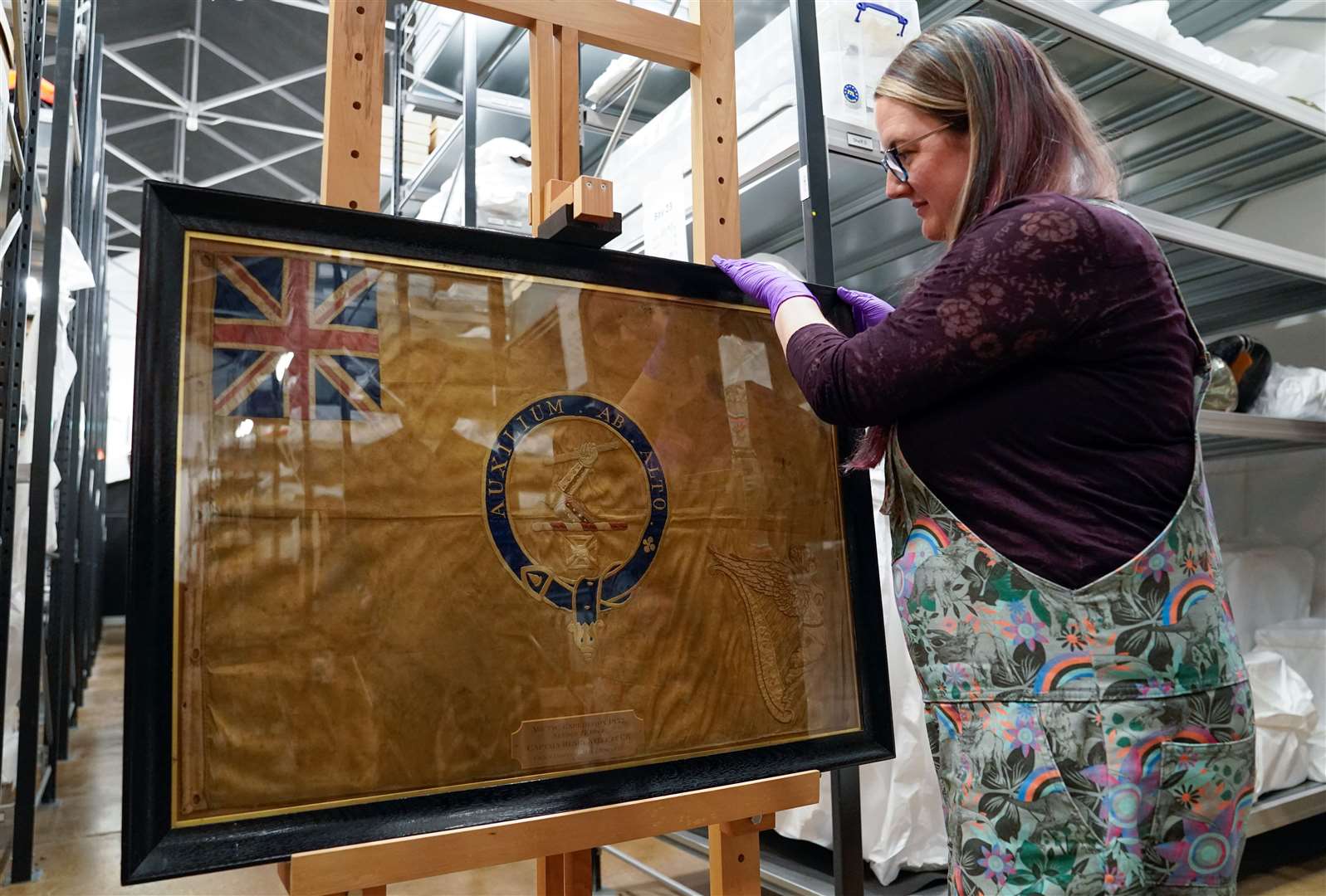 A conservator from the National Museum of the Royal Navy adjusts the Kellet Sledge flag in it’s frame at Portsmouth Historic Dockyard in Hampshire. Picture date: Wednesday May 16, 2023. (Andrew Matthews, PA)