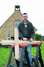 Carpenter Matthew Austen prepares the new cross