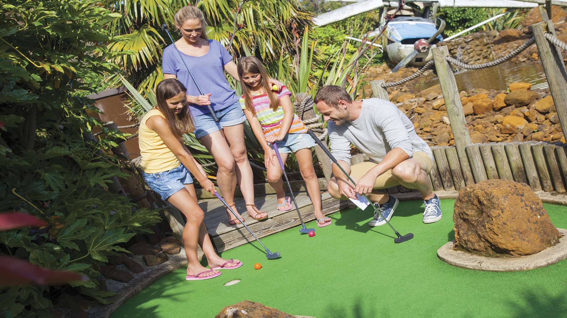 A family enjoying a round of crazy golf at the park.