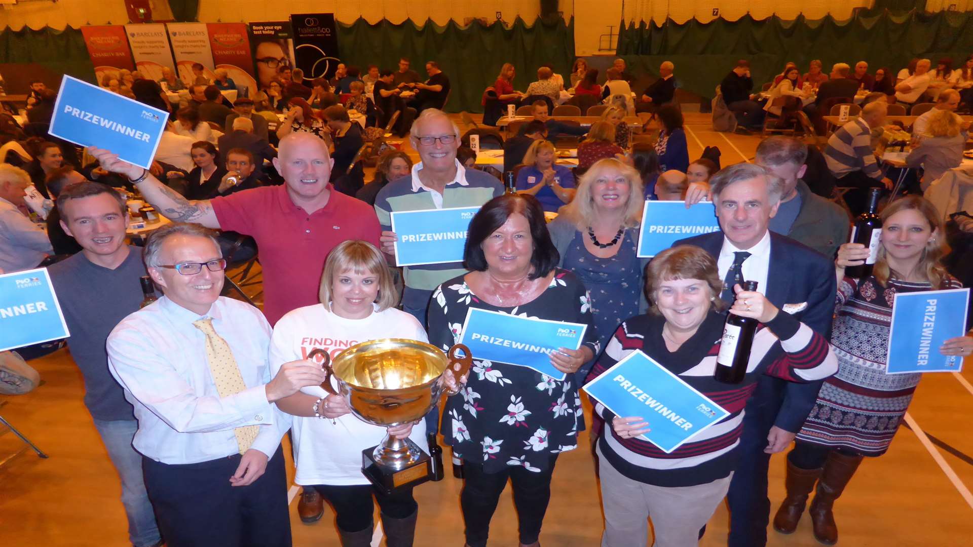 KM Ashford Big Charity Quiz event partners Carly James of HR GO, Richard Rix of Hallett and Co and Clive Perry of Specsavers present the winners trophy to the Moomins.